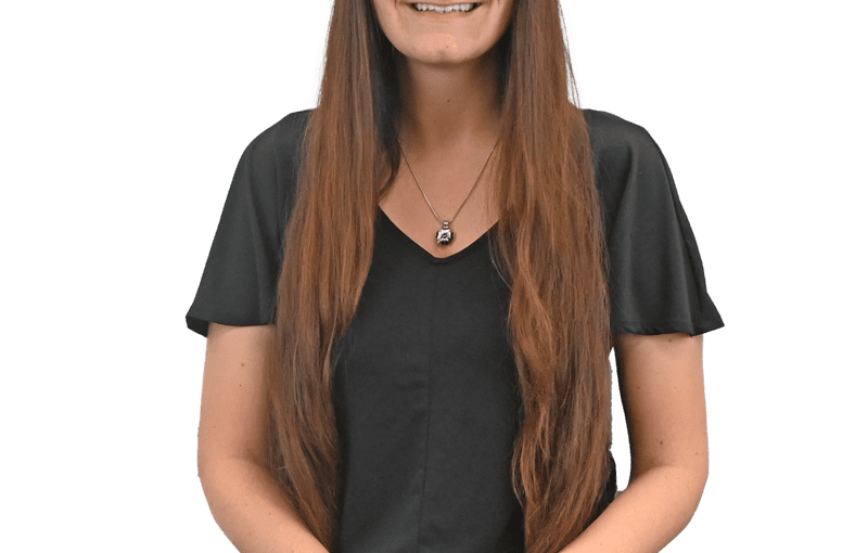 Alicia Hill, SSA, smiling at camera wearing glasses, black v-neck shirt and gray pants in professional headshot