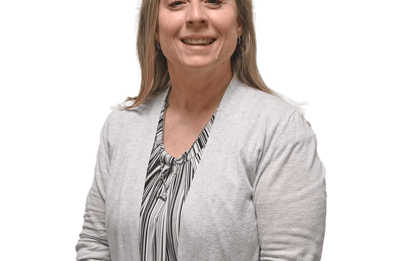 Heidi Clark, Community Connections Coordinator, smiling in professional headshot wearing light cardigan and striped blouse with glasses on head
