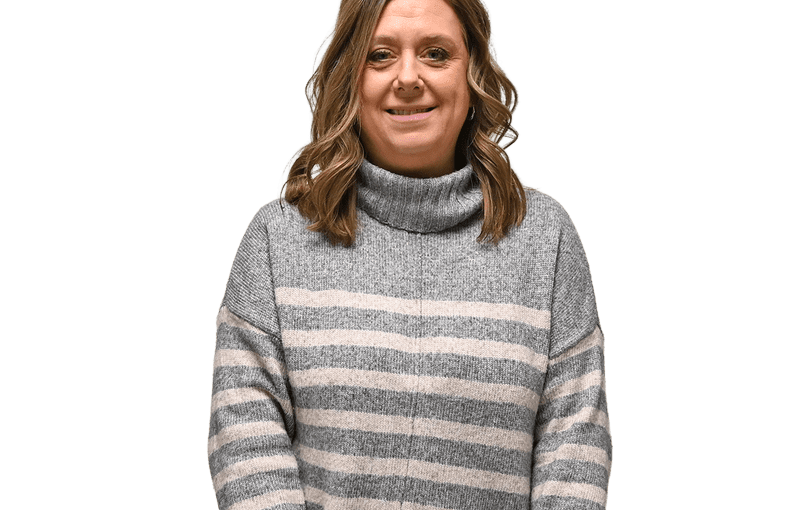 Jami Hill, EI Service Coordinator, smiling at camera wearing gray and cream striped turtleneck sweater