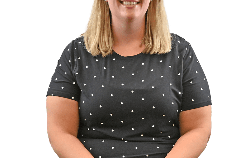 Joy Ruetz, Community Connections Coordinator, smiling at camera wearing glasses and polka dot shirt