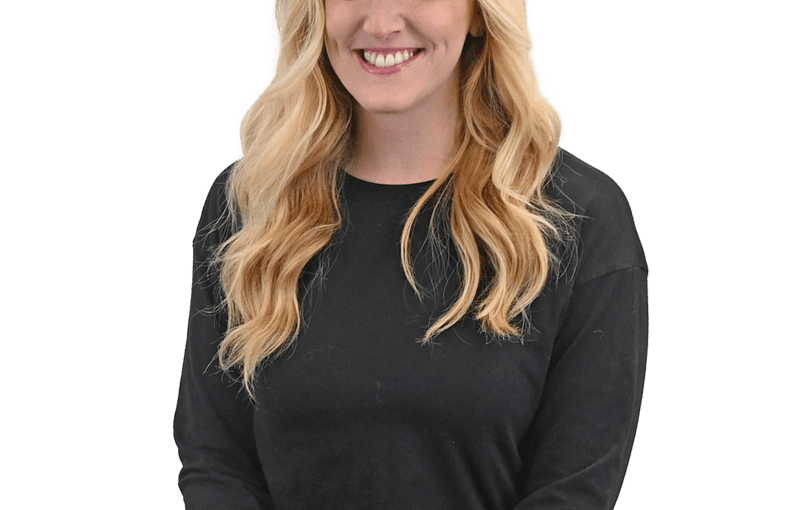 Kayla Phillips, Early Intervention Developmental Specialist, smiling at camera wearing black long-sleeve shirt and light jeans against white background