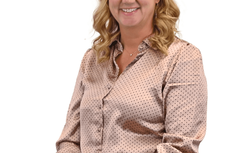 Kelly Jordan, Service and Support Administrator smiling at camera wearing pink polka dot blouse against white background