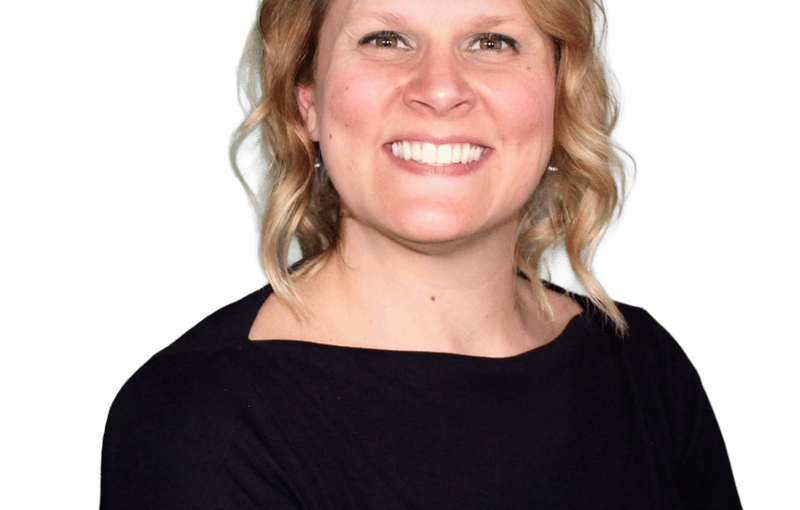 Lea Perrine, Investigative Agent, smiling woman with shoulder-length wavy blonde hair wearing a black long-sleeved shirt against a white background