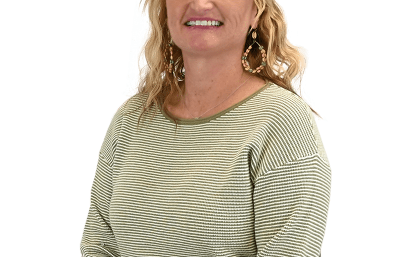 Ruth Watson, Director of Youth and Provider Services, smiling in a green striped long-sleeve shirt and tan pants against a white background