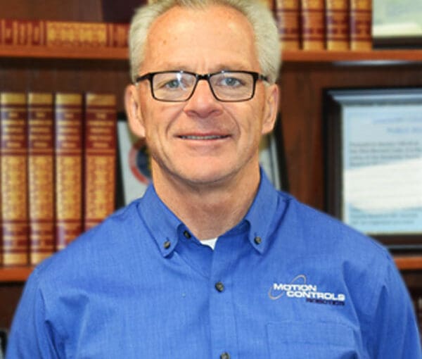 Tim Ellenberger, professional wearing blue Madison Controls polo shirt, smiling in office with law books in background