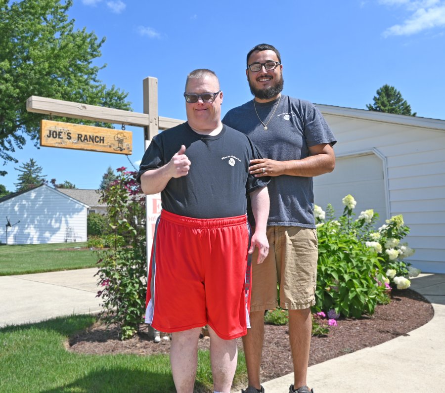 Two men standing outside Joe's Ranch facility in Sandusky County Ohio, smiling at camera with residential building and landscaping visible behind them
